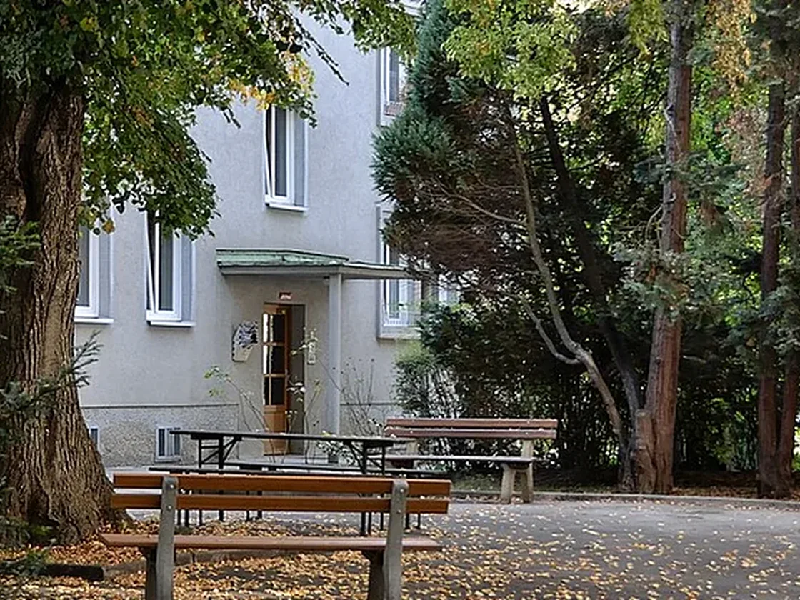 Begrünter Wohnhof mit mehreren Gebäudeteilen und Wohnungen