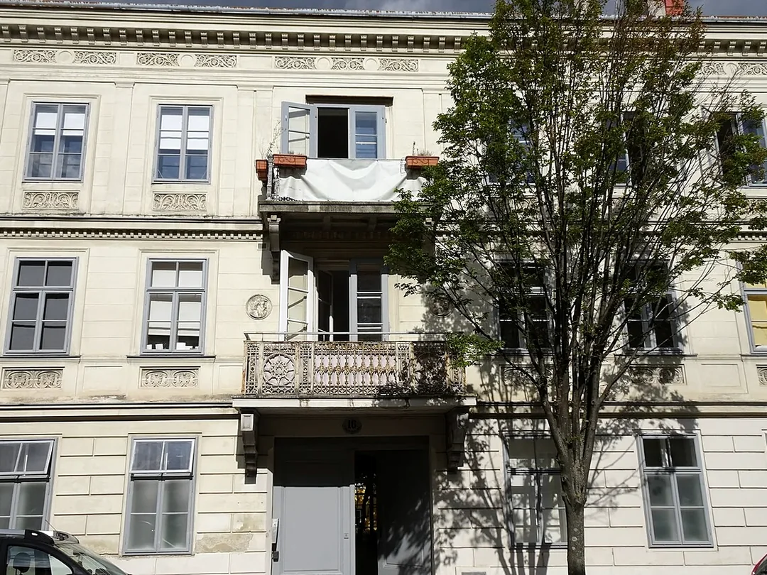 Wohnhausfassade mit mehreren Fenstern, Balkonen und getrennten Einheiten